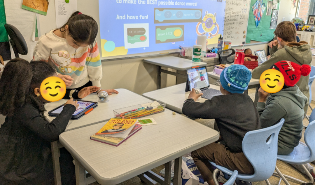 Youth in a classroom setting at desks exploring tablets and coding.